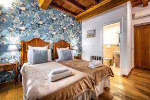 Habitación de hotel con dos camas, cabeceros de madera y un diseño de papel tapiz floral.