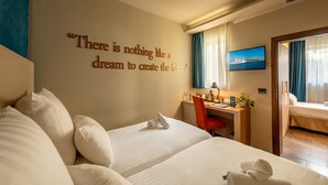 Ein Hotelzimmer mit einem großen Bett, einem Schreibtisch und einem an der Wand befestigten Fernseher.