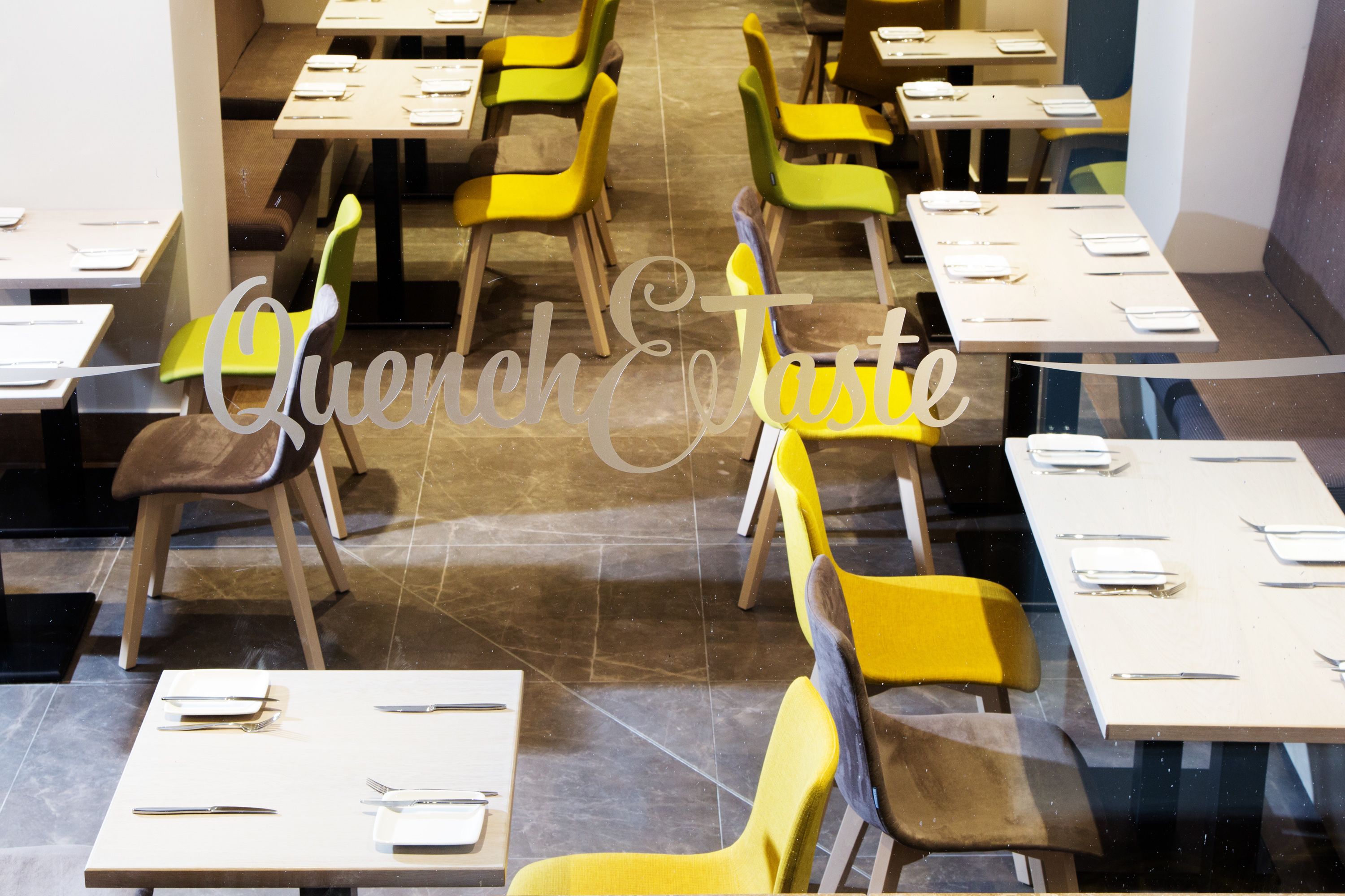 A restaurant with multiple tables and chairs, each set with cutlery and napkins.