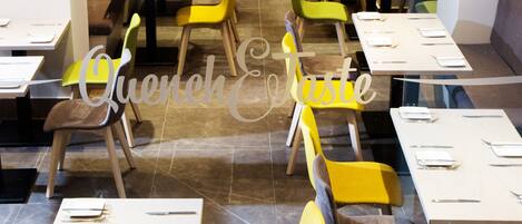 A restaurant with multiple tables and chairs, each set with cutlery and napkins.