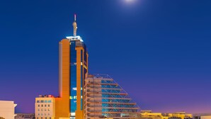 Ein modernes Hochhaus mit einem markanten Turm und einer außergewöhnlichen pyramidenartigen Struktur.