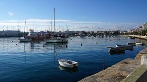 Ein Yachthafen mit mehreren angedockten Booten, darunter ein markantes rotes und weißes Schiff namens 'Captain Morgan', und einem strahlend blauen Himmel.