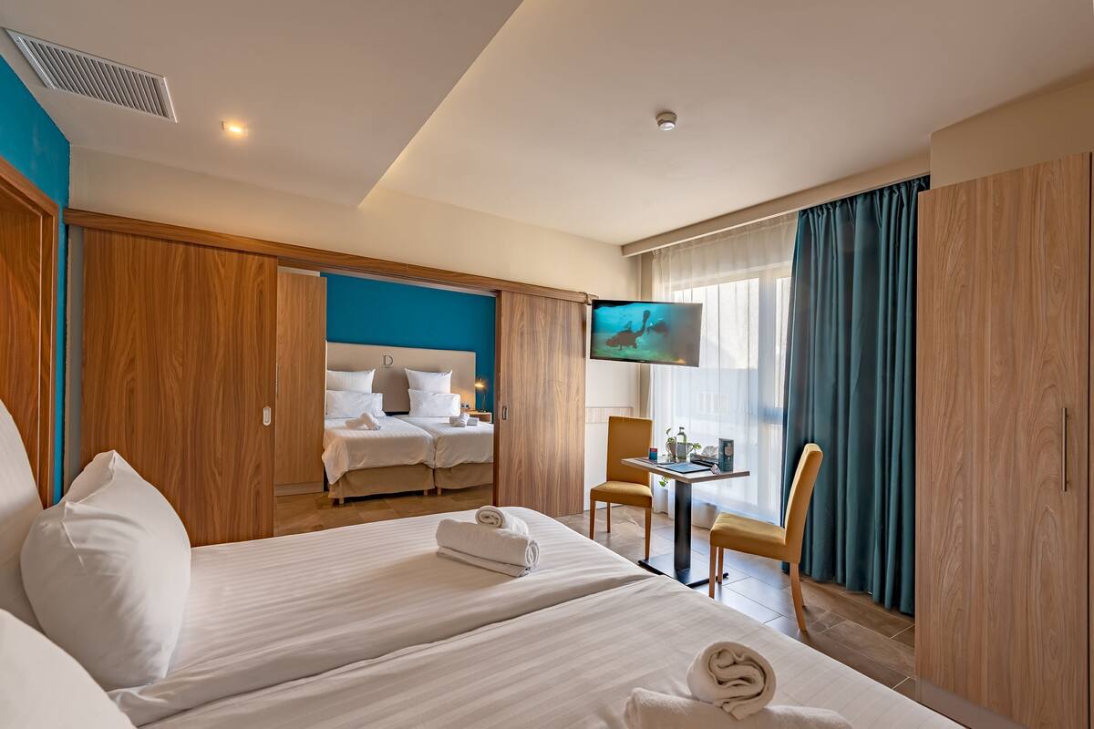 A hotel room with two beds, a TV, a desk, and a chair.