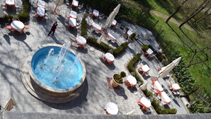 Un patio al aire libre con mesas y sillas, una fuente central y un sendero.