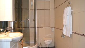 A bathroom with a glass-enclosed shower, a toilet, and a sink.