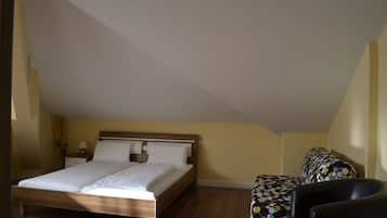 A bedroom with a wooden bed, a nightstand, a chair, and a patterned sofa.