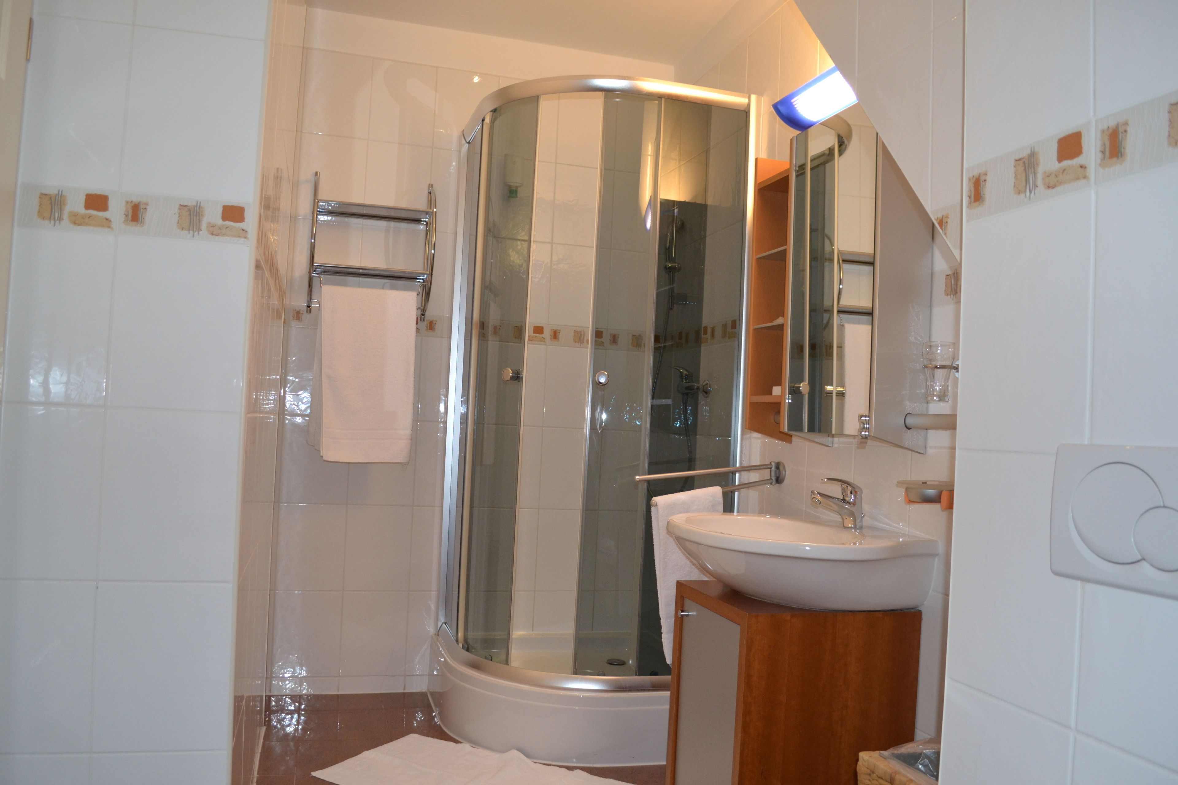 A modern bathroom with a glass-enclosed shower, a white sink, and a wooden vanity.