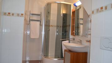 A modern bathroom with a glass-enclosed shower, a white sink, and a wooden vanity.