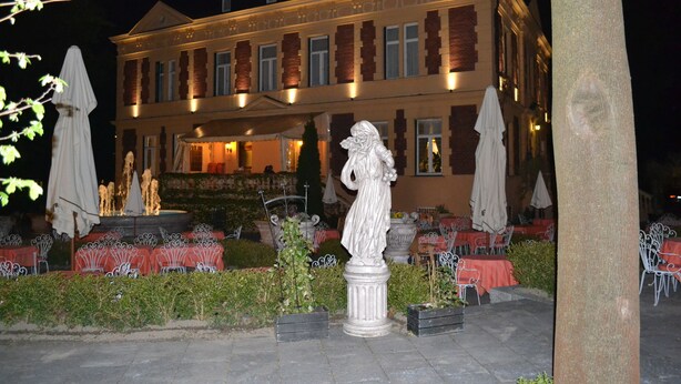 Un edificio con una fuente, asientos al aire libre y una estatua.