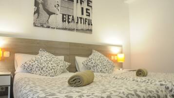 A hotel room with two beds, patterned bedding, a wooden headboard, and a motivational quote on the wall.