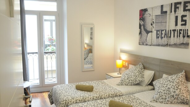A hotel room with two beds, a large window, a mirror, and a motivational poster on the wall. - Old City House (San Sebastián)