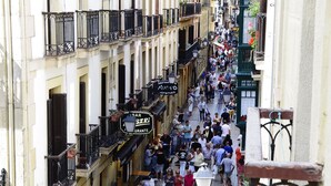 A bustling urban street with pedestrians and shops. - Old City House (San Sebastián)