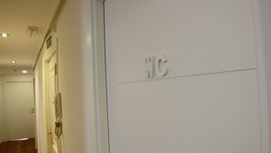 A hallway with a door marked "JC" and an emergency exit sign. - Old City House (San Sebastián)
