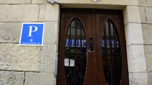 A building entrance with a brown door, a blue parking sign, and a number 14 plaque. - Old City House (San Sebastián)