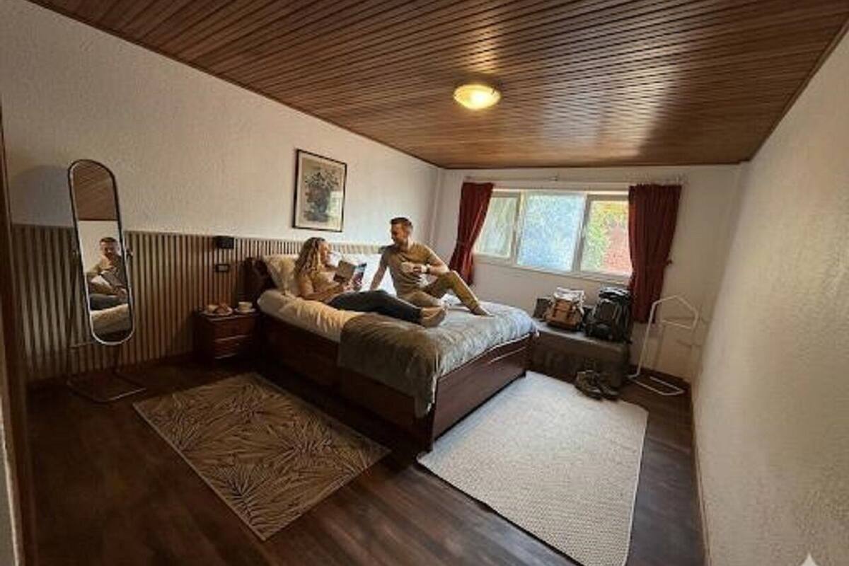 Ein Schlafzimmer mit Bett, Spiegel, Fenster und Heizkörper.