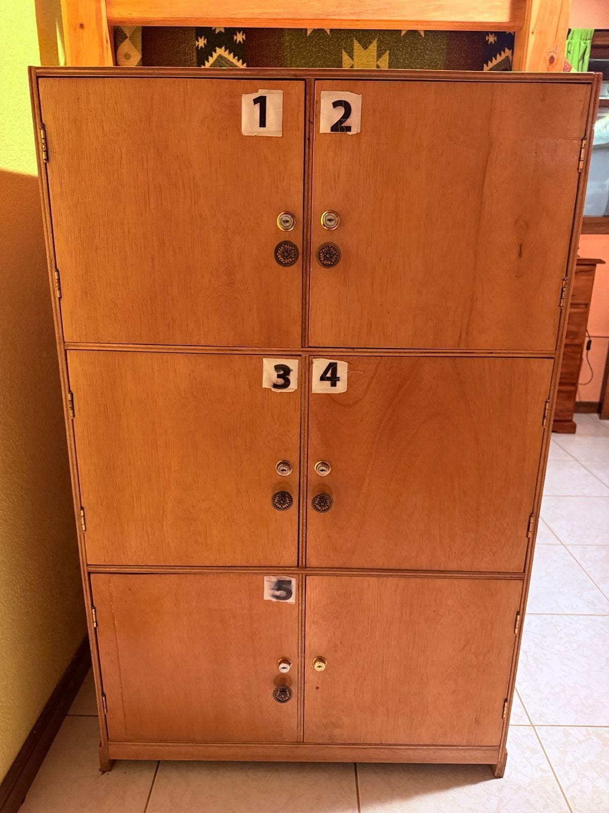 A wooden cabinet with four numbered compartments, each with a lock.
