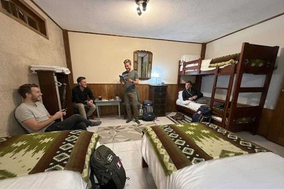 Ein Zimmer mit zwei Betten, einem Tisch und einem Spiegel.