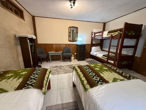 A room with two beds, a chair, a desk, a mirror, and a bunk bed.