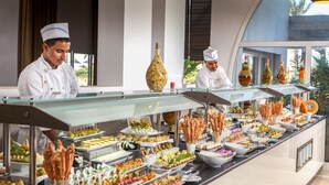 Un bufé con diversos alimentos y un chef con uniforme.
