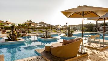 Área da piscina com espreguiçadeiras, guarda-sóis e vista desobstruída da piscina.
