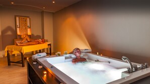 Un cuarto de spa con una bañera grande, una mesa con un mantel amarillo y velas.