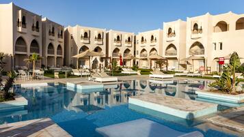 Un hotel con varios balcones, piscina y zonas de estar al aire libre.