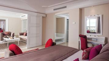 A spacious bedroom with a large bed, a sitting area with a sofa and coffee table, and a walk-in closet.