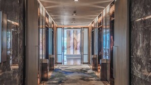 A modern hallway with a marble floor, glass doors, and a view of the city.