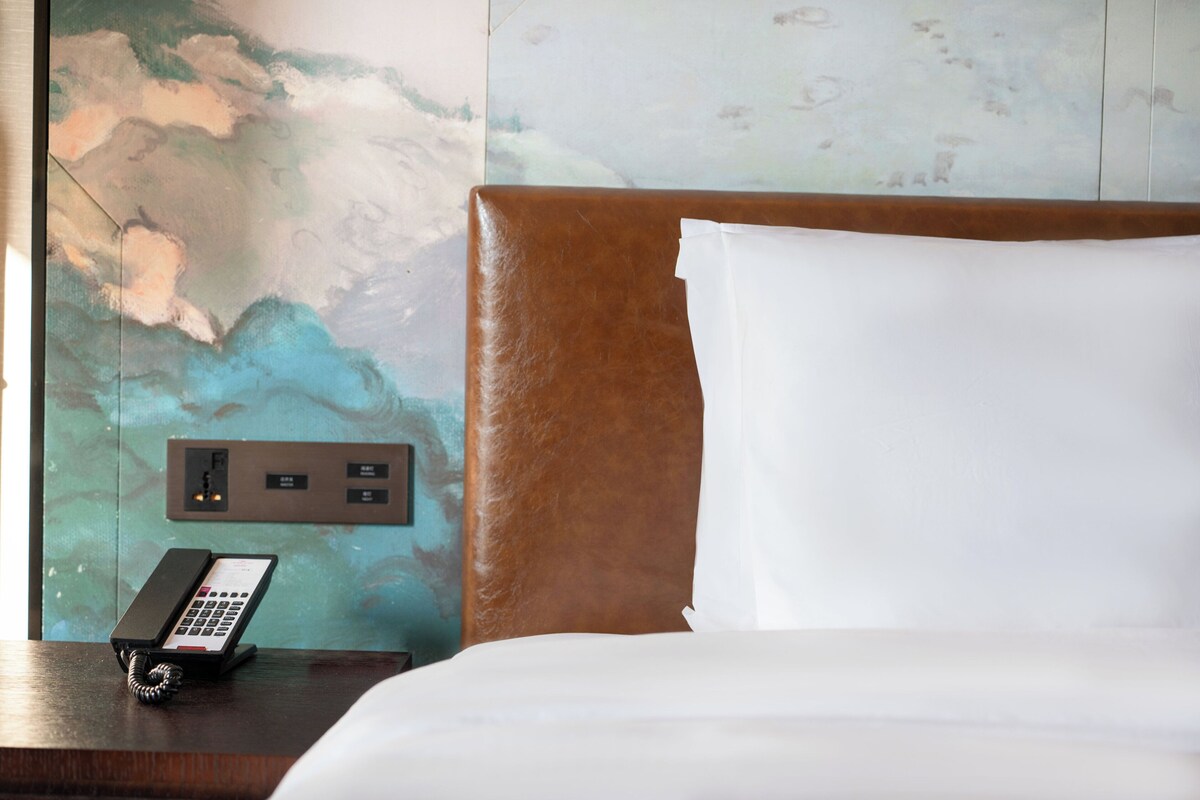 Ein Hotelzimmer mit einem Bett, einem Telefon und einer Wand mit strukturierter Gestaltung.
