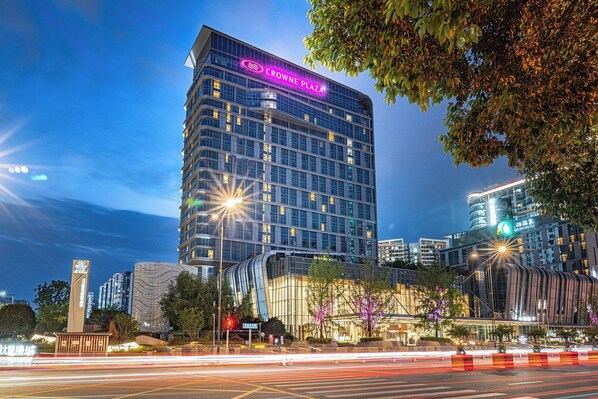 A modern high-rise hotel with a prominent "Crowne Plaza" sign, surrounded by urban infrastructure and nighttime lighting. - Crowne Plaza Chengdu Wenjiang by IHG (Chengdu)