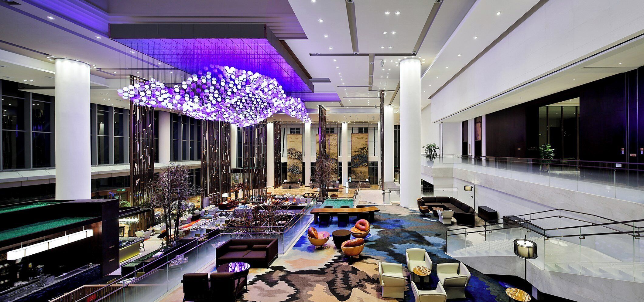 A spacious lobby with a high ceiling, a central seating area, and a large chandelier.