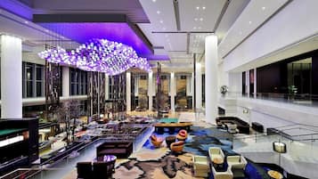 A spacious lobby with a high ceiling, a central seating area, and a large chandelier.
