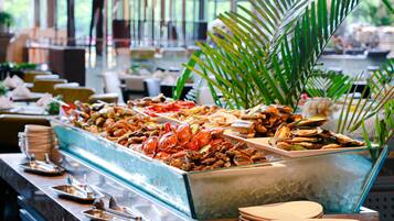 A buffet with seafood and a palm tree in the background.