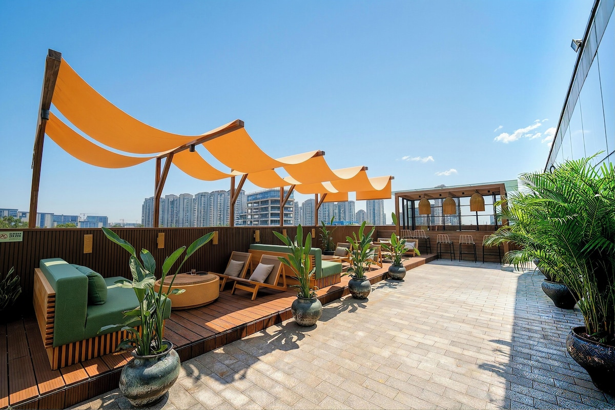 Terraço no telhado com piso de madeira, área de estar externa e plantas em vasos.