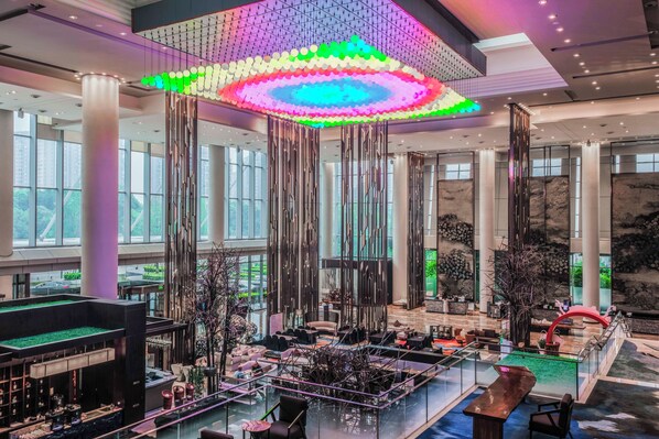A spacious lobby with a high ceiling, large windows, and a central seating area with a glass barrier. - Crowne Plaza Chengdu Wenjiang by IHG (Chengdu)