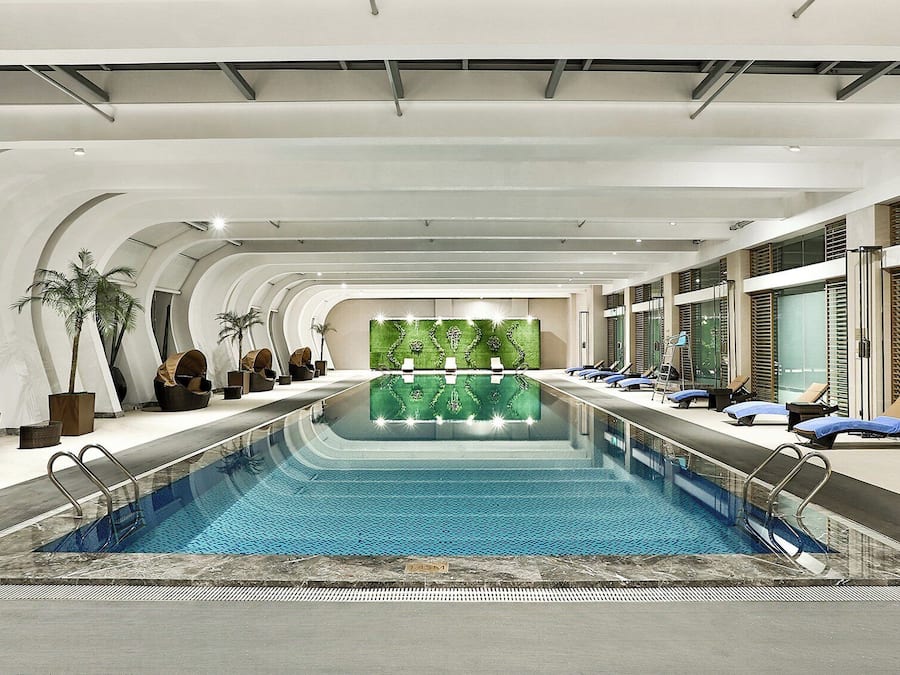 Una piscina interior moderna con sillas de descanso y zonas de estar.