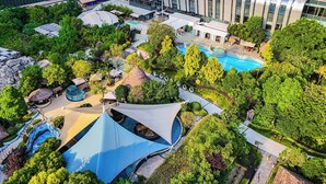 A modern hotel complex with a swimming pool, lush greenery, and contemporary architecture.