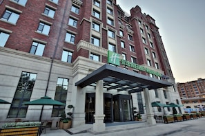 A hotel entrance with a modern design, featuring a large glass door and a covered entrance area.