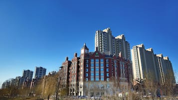 Un edificio de varios pisos con una imponente torre de reloj, probablemente un hotel, rodeado de otros edificios altos.