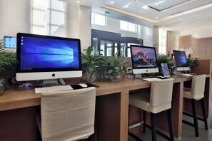 Un espace de bureau moderne équipé de plusieurs ordinateurs Apple iMac, d’un clavier blanc et d’une chaise de couleur beige.