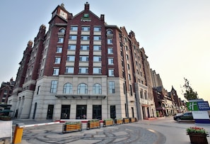 A multi-story Holiday Inn Express building with a prominent clock tower, large windows, and a landscaped entrance area. - Holiday Inn Express Langfang Park View by IHG (Langfang)