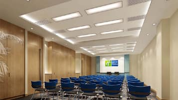 A conference room with rows of blue chairs, wooden paneling on the walls, and a sign for Hyatt Express in the background.