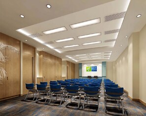 Une salle de conférence avec des rangées de chaises bleues, un lambris en bois sur les murs et, au fond, une enseigne Hyatt Express.