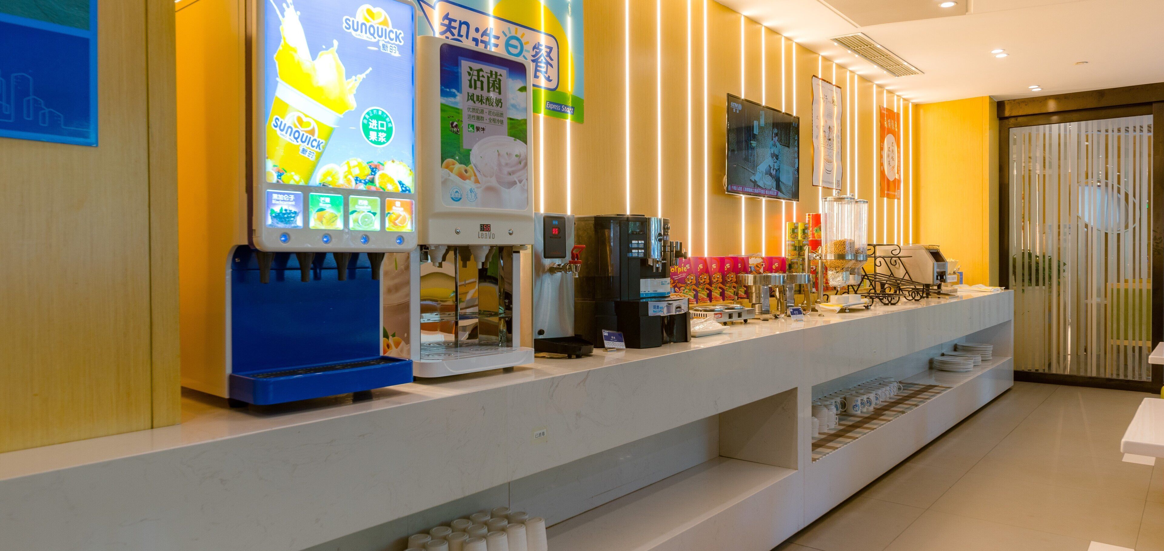 A hotel reception area with a counter, vending machines, and a television screen.