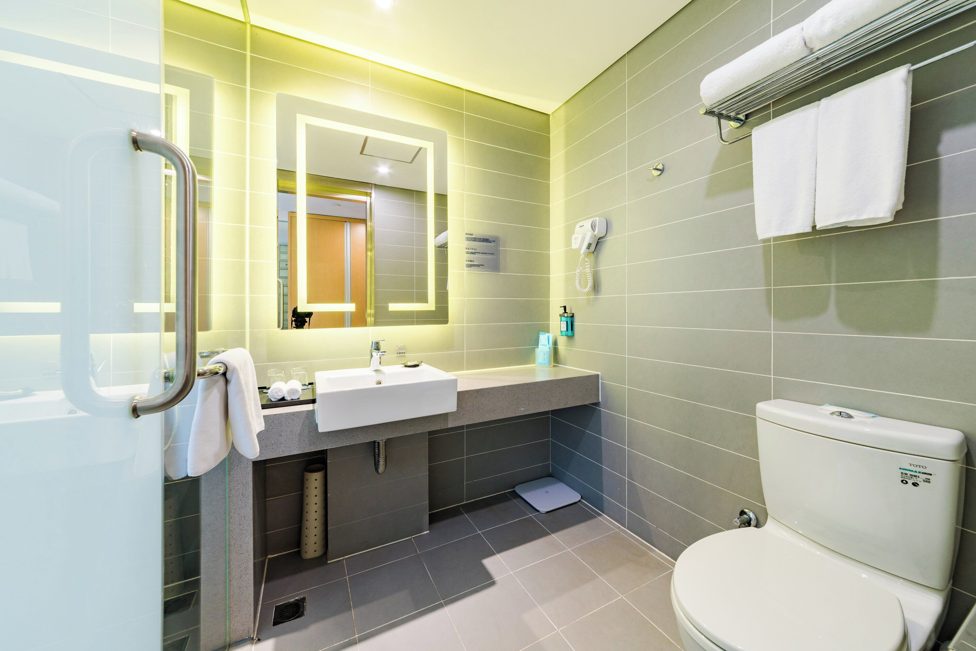 Un baño moderno con lavamanos, espejo, toallero y retrete.