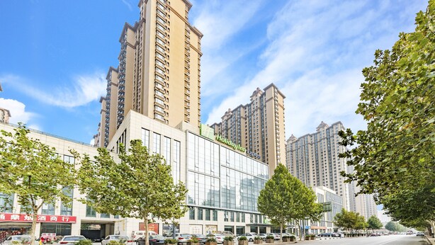 A modern hotel with a glass facade, located in a high-rise urban area with surrounding high-rise buildings. - Holiday Inn Express Shijiazhuang Heping by IHG (Shijiazhuang)
