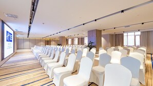 A conference room with rows of white chairs, a wooden floor, and a large screen on the left wall. - Holiday Inn Express Shijiazhuang Heping by IHG (Shijiazhuang)