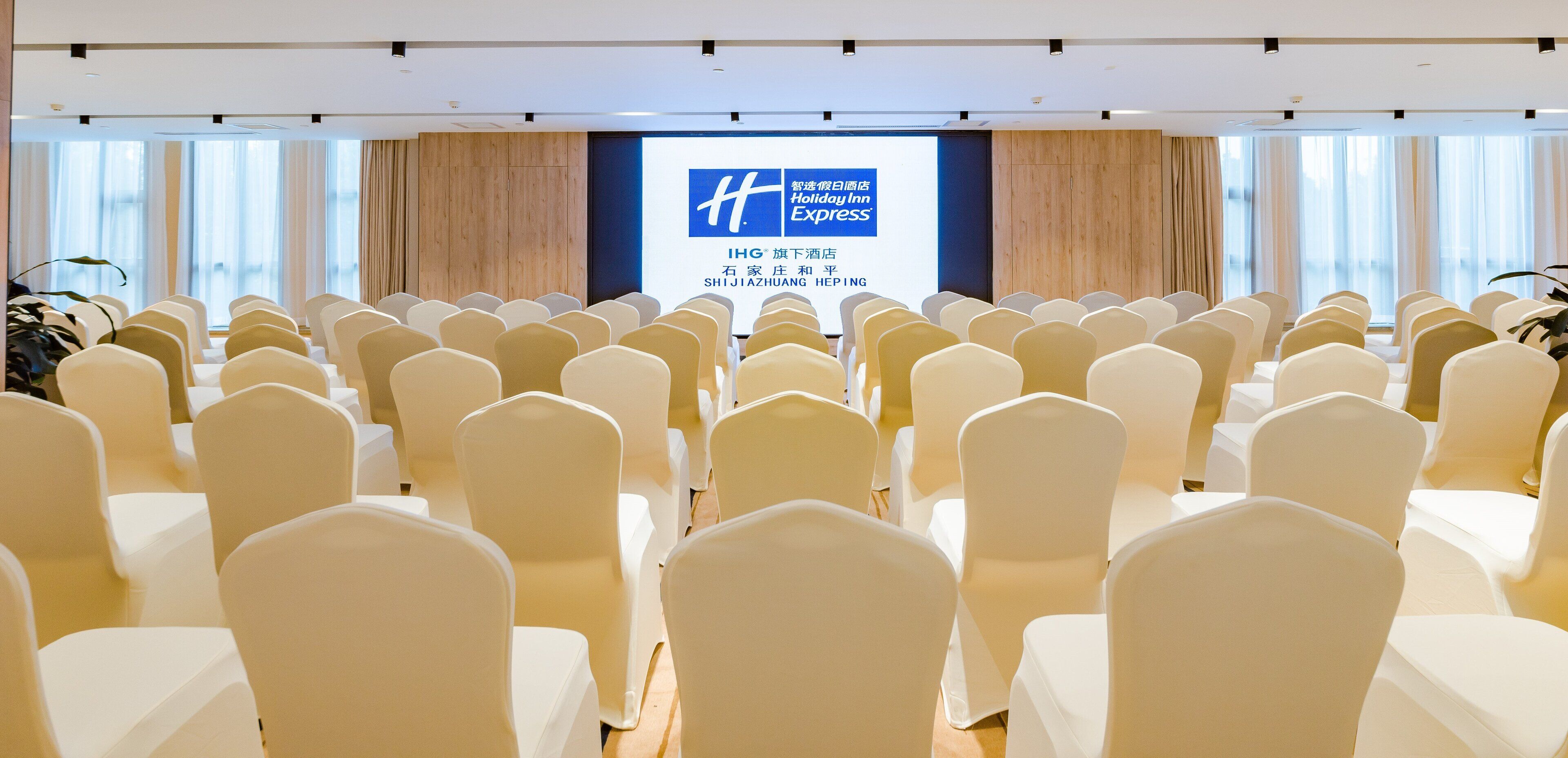 A conference room with rows of chairs facing a screen displaying the Holiday Inn Express logo.