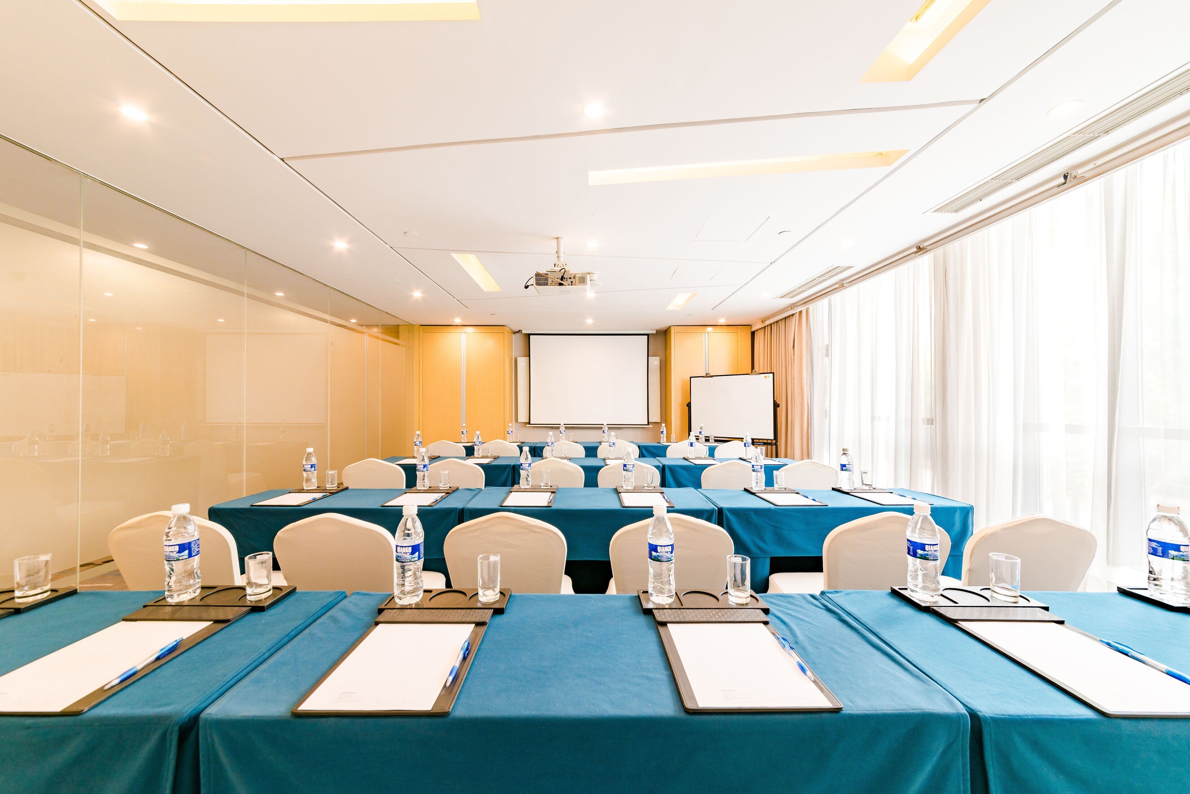 Une salle de conférence avec des tables disposées pour les réunions, équipée de bouteilles d’eau et de plaques nominatives.