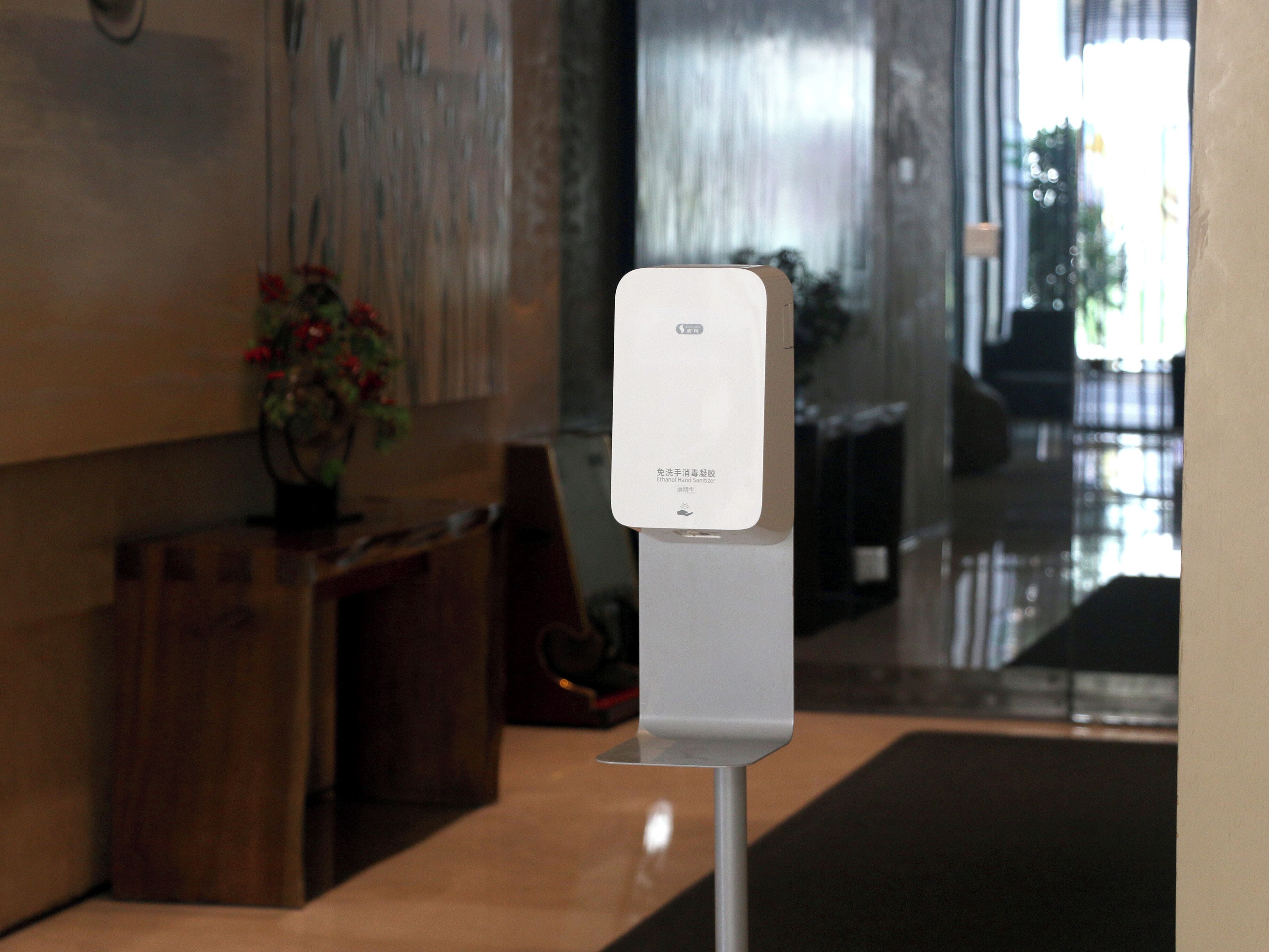 A hand sanitizer dispenser mounted on a wall in a lobby area.